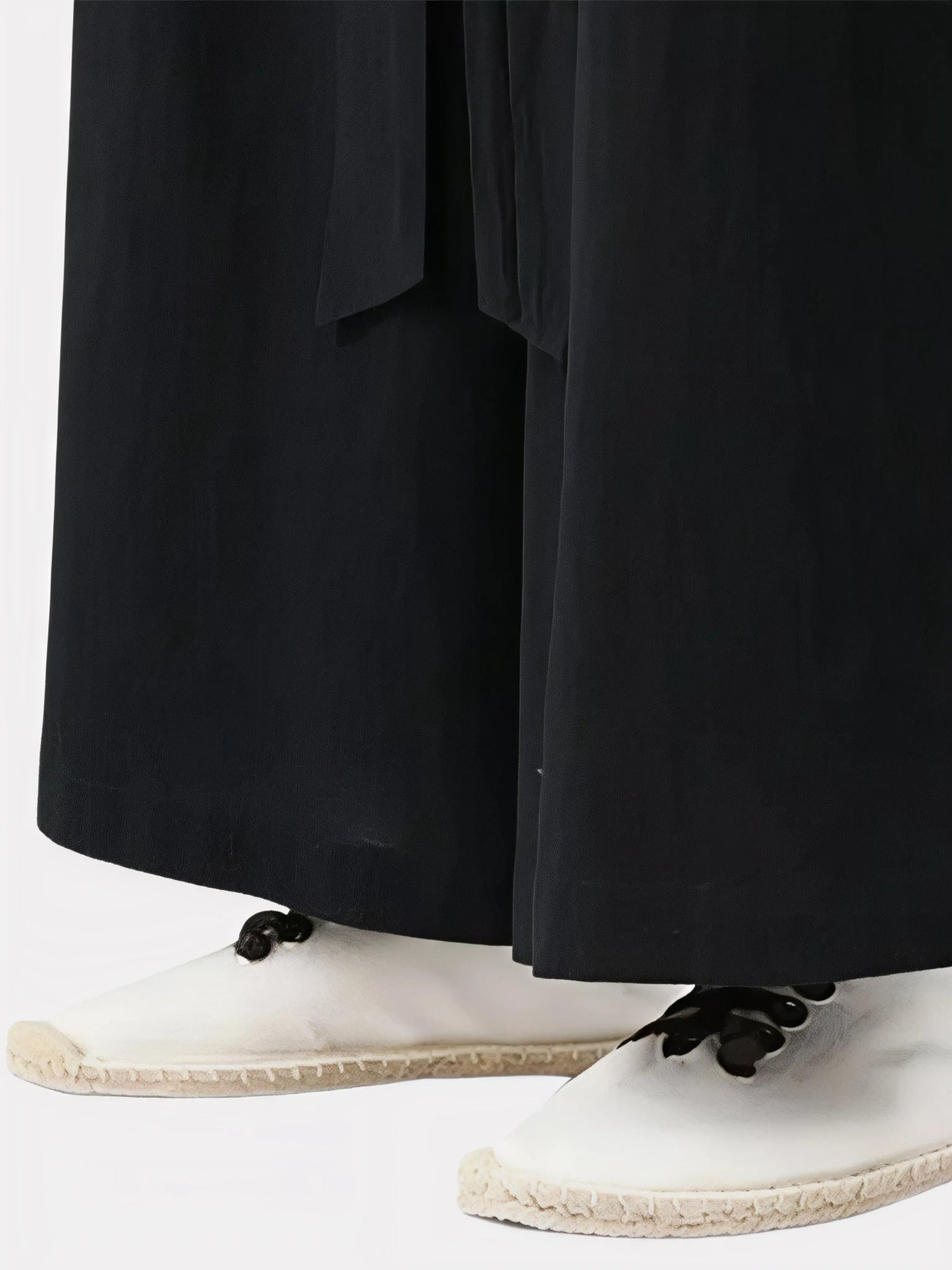 Zoom sur le bas du pantalon japonais noir, tissu fluide et finition droite avec coupe ample typique du style japonais.